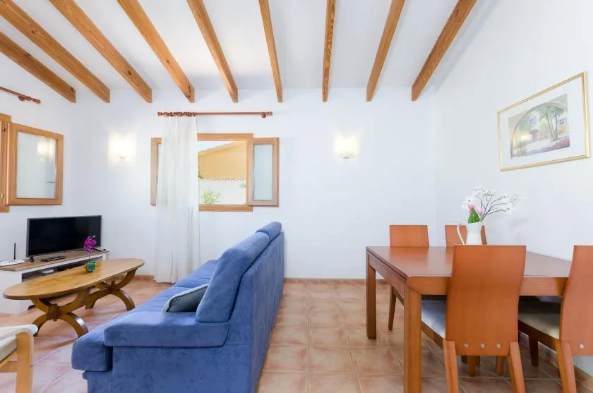 Una luminosa sala de estar y comedor con asientos azules y una mesa de madera.