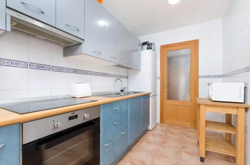 Una cocina compacta con gabinetes azules, una encimera y electrodomésticos integrados.