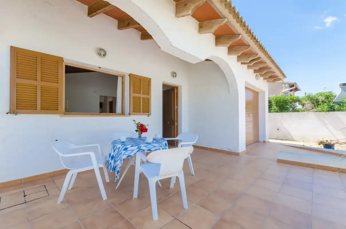Un patio exterior embaldosado con una mesa y asientos junto a la casa.