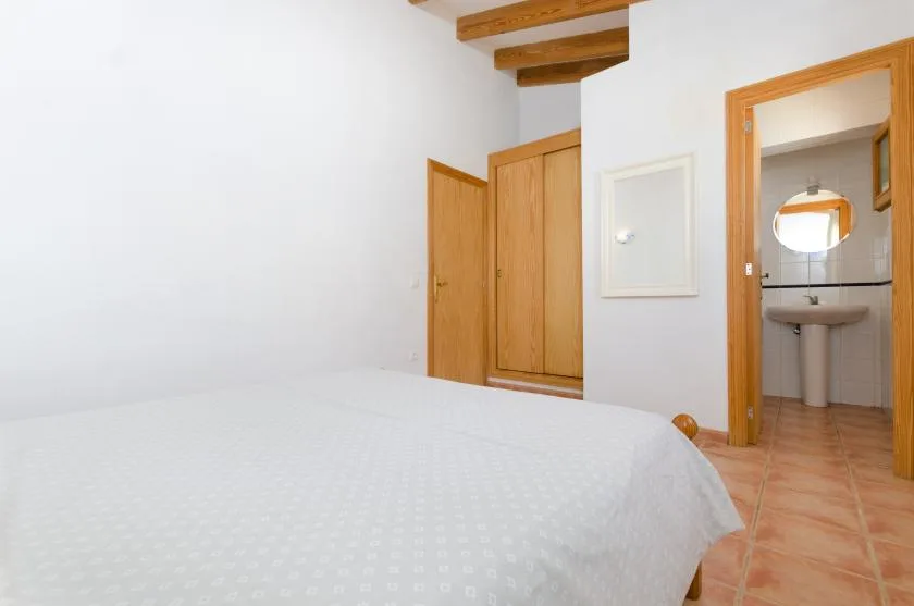 Un dormitorio con una cama blanca y una puerta que da a un baño.