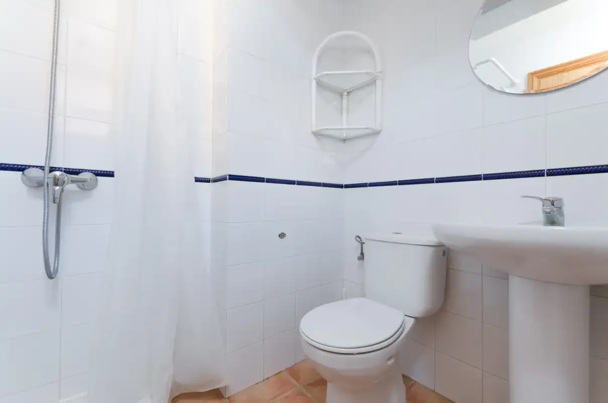 Un baño alicatado con inodoro, lavabo y ducha.