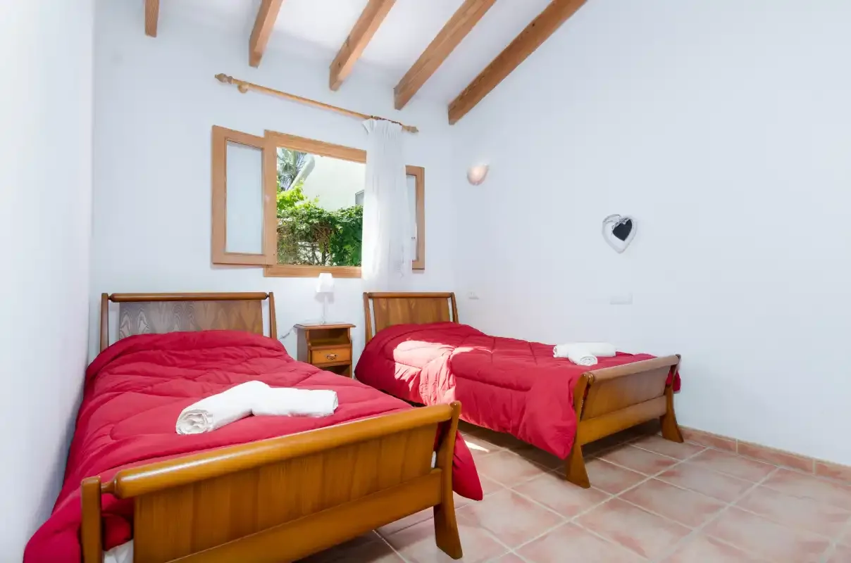 Un dormitorio con dos camas de madera vestidas con ropa de cama roja y toallas.