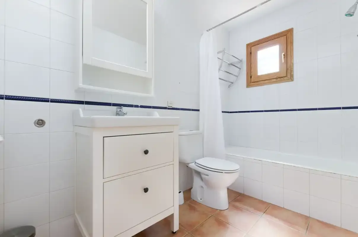 Un baño con azulejos, lavabo, inodoro y bañera.