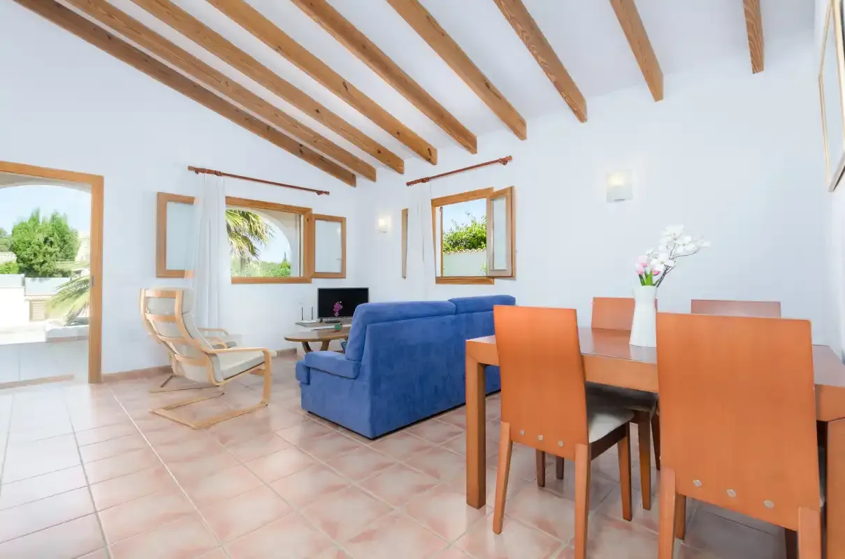 Una luminosa sala de estar y comedor tiene asientos azules y una mesa de madera.