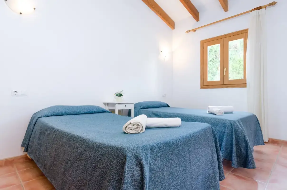 Un dormitorio con dos camas, cada una con toallas dobladas.