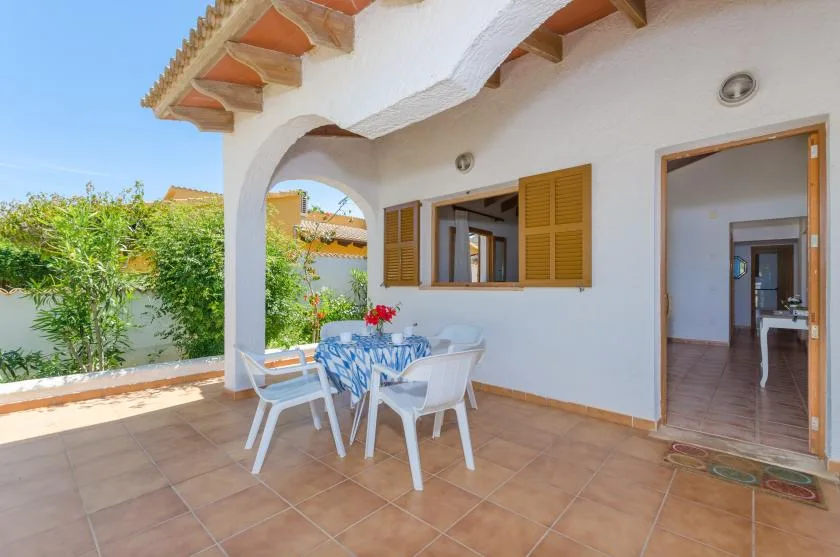 Un patio cubierto con una mesa y sillas junto a una puerta abierta.