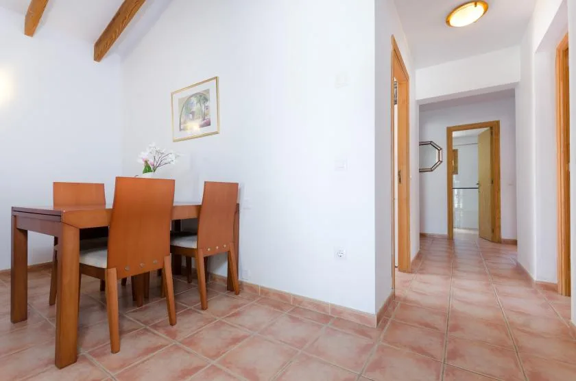 Comedor con asientos de madera junto a un pasillo.