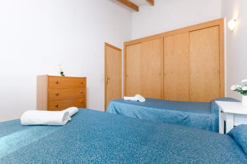 Un dormitorio con dos camas, armarios de madera y toallas dobladas.