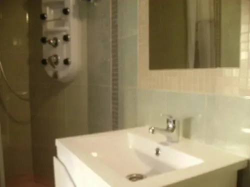 Baño con lavabo blanco, espejo y ducha con mampara.
