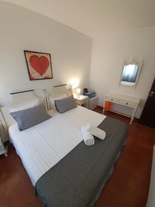 Habitación doble económica con ropa de cama blanca, almohadas azules y lámpara de noche.