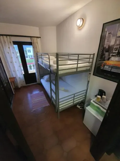 Dormitorio compartido económico con literas metálicas y acceso al balcón.
