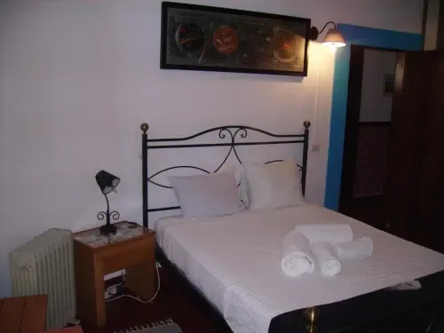 Habitación doble con cama de hierro forjado, ropa de cama blanca, mesa de noche y radiador.