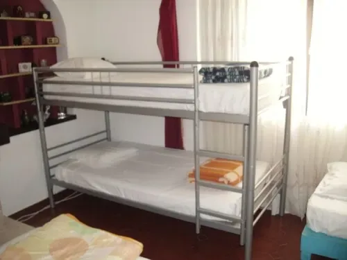 Litera metálica con ropa de cama blanca en una habitación compartida.