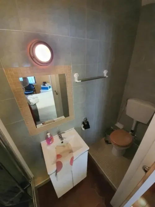 Baño con lavabo, inodoro, espejo iluminado y paredes revestidas de azulejos.