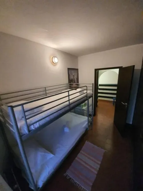 Dormitorio compartido económico con literas metálicas y vistas a las montañas.