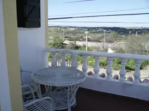 Terraza de balcón con sillas de mimbre blanco y vistas a las colinas y al valle.