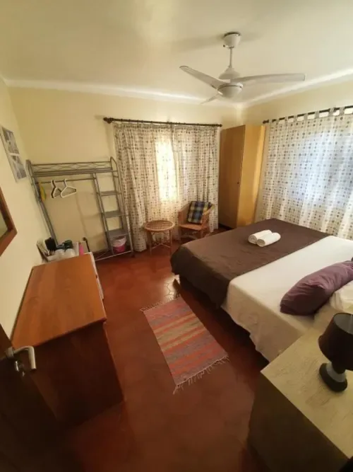 Habitación doble con camas, ventilador, muebles de madera y vistas al jardín.