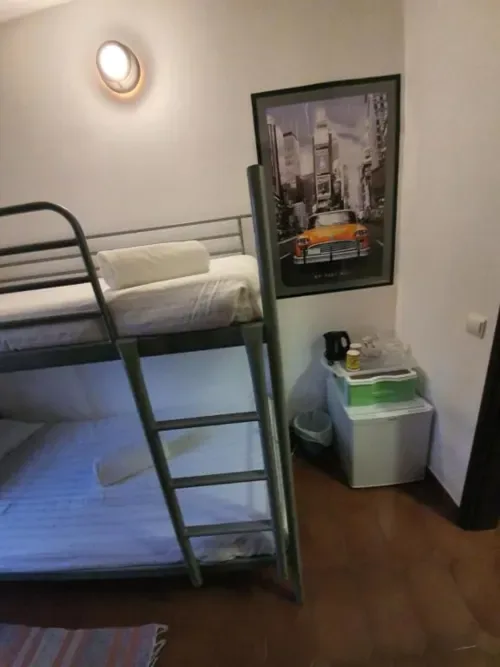 Habitación económica con literas metálicas y minibar.