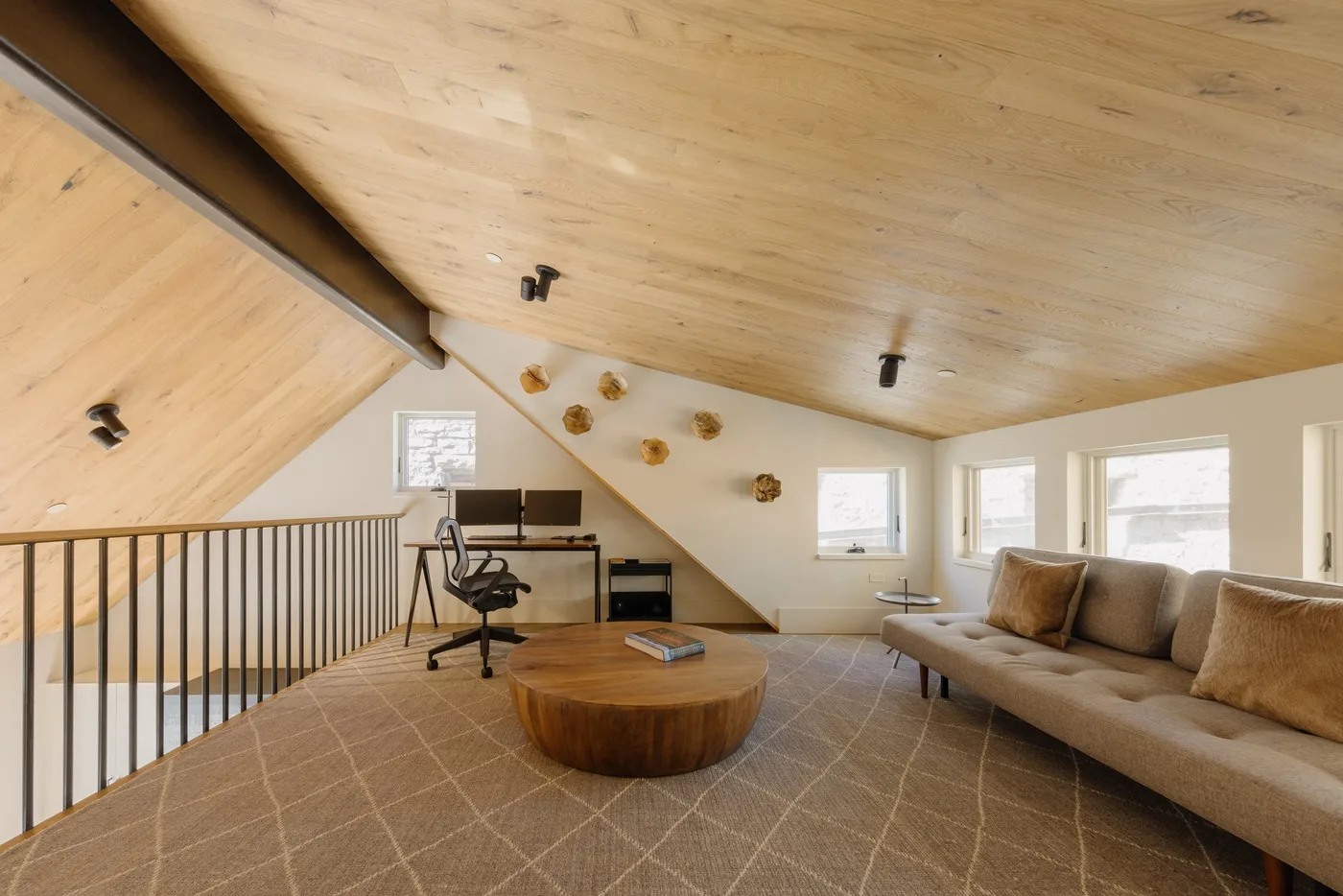 Una luminosa sala de estar tipo loft con escritorio, asientos y ventanas.
