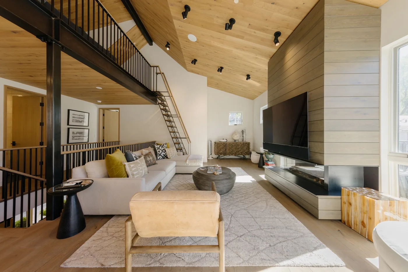 Una sala luminosa con techo alto de madera, asientos y un televisor grande.