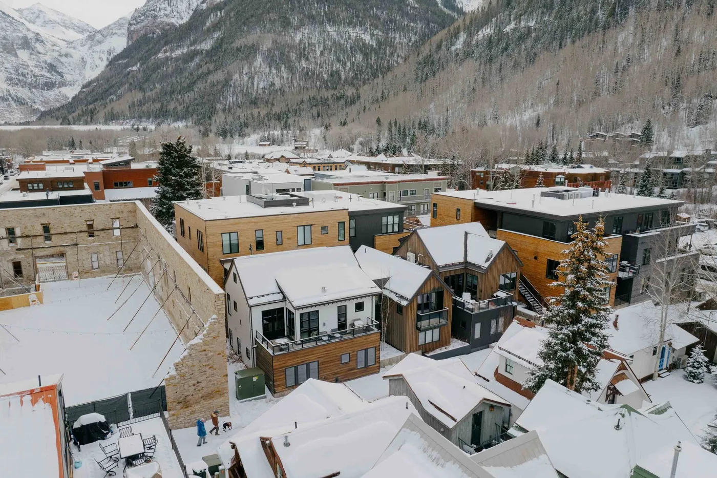 Edificios cubiertos de nieve se encuentran en un valle montañoso bajo laderas boscosas.