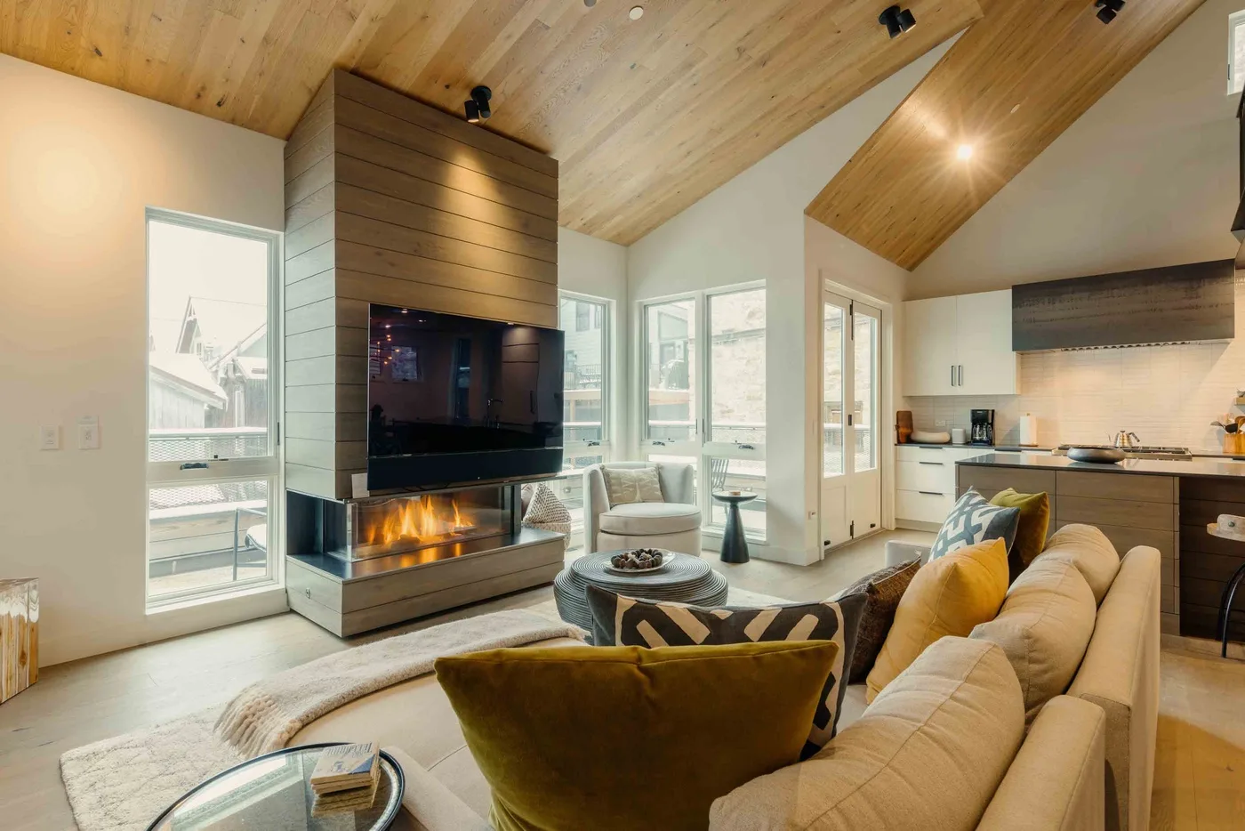 Una luminosa sala de estar de planta abierta con chimenea y cocina contigua.