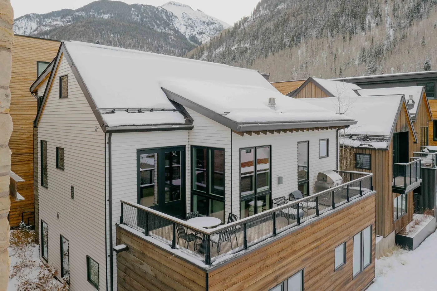 Casas modernas cubiertas de nieve con balcones frente a las montañas.