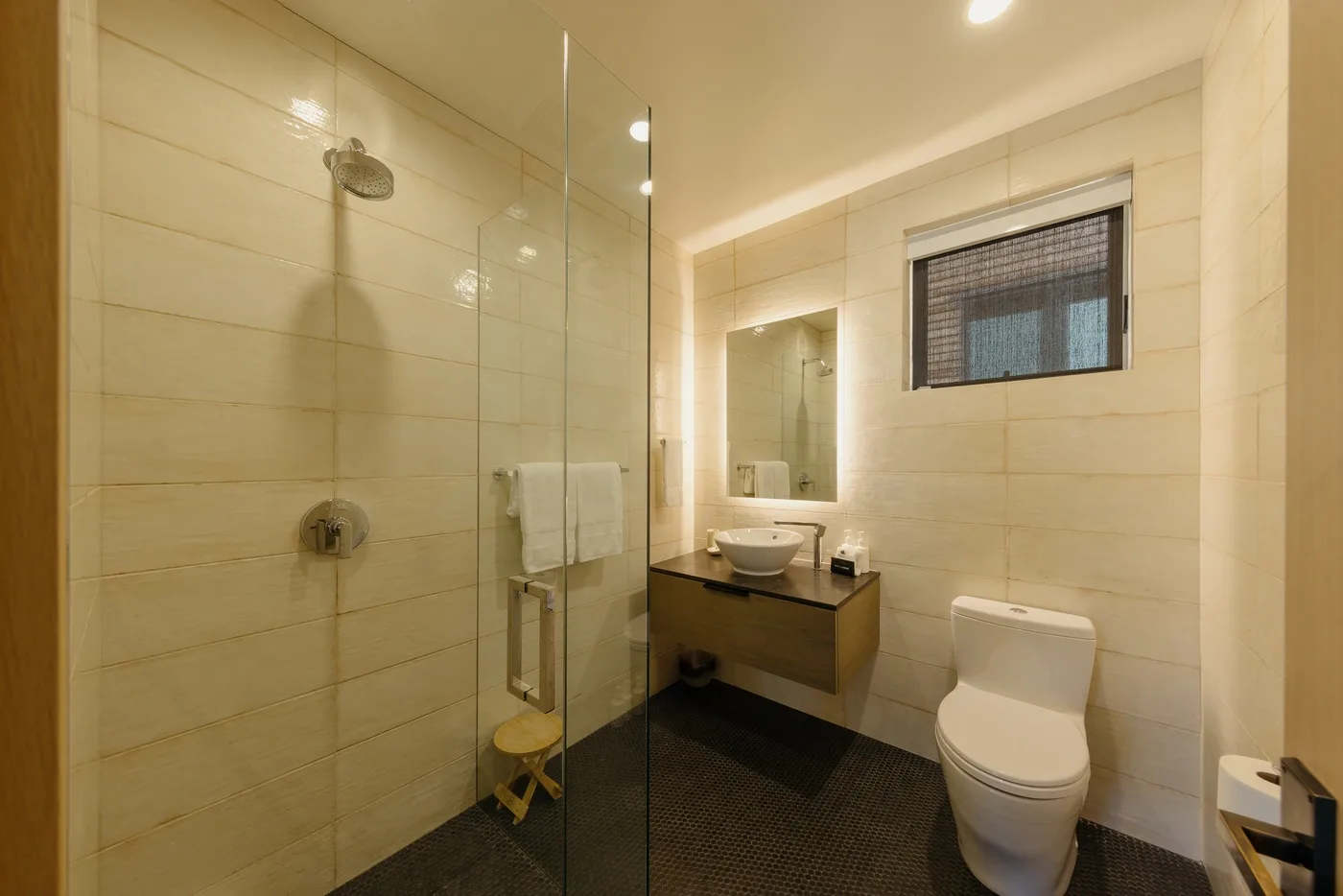 Un baño con azulejos, ducha de vidrio, lavabo y inodoro.
