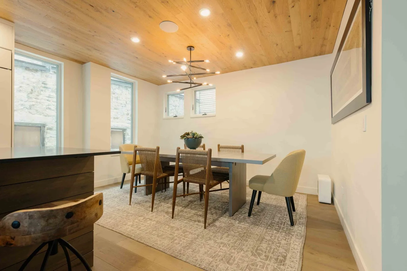 Comedor con una mesa de madera y sillas bajo un techo revestido de madera.