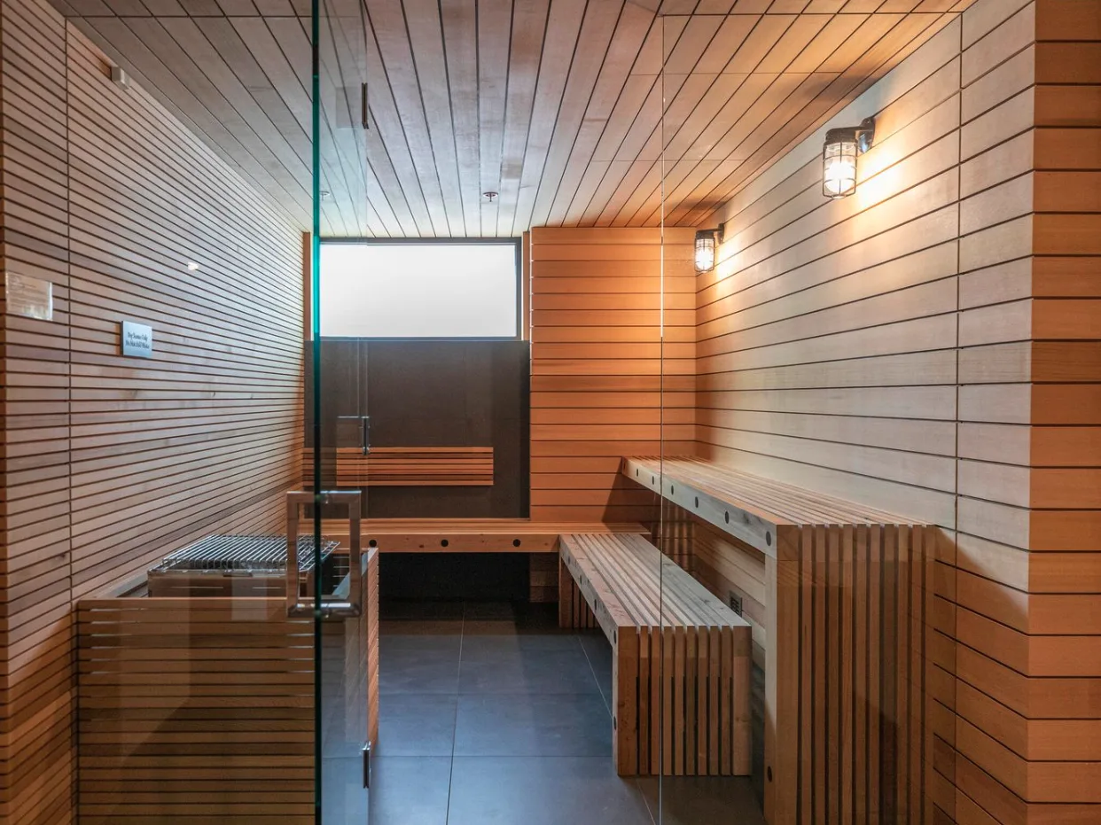 Una sauna revestida de madera, con asientos escalonados y suelo de baldosas.