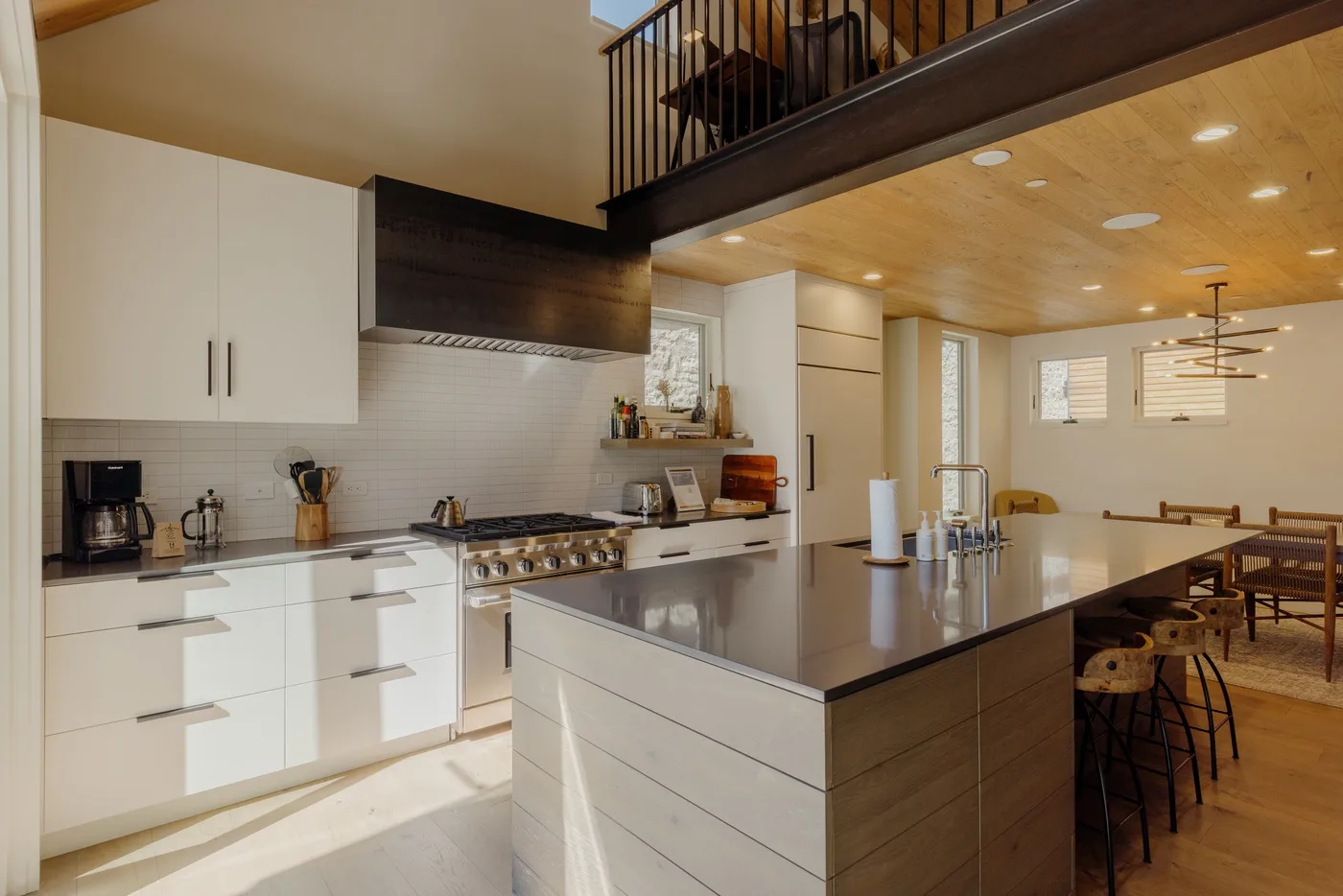 Una cocina moderna con gabinetes blancos e isla central se abre a un comedor.