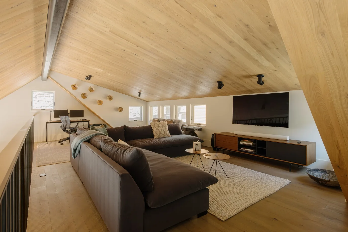 Una sala de estar tipo loft con una amplia zona de asientos y un televisor en la pared.