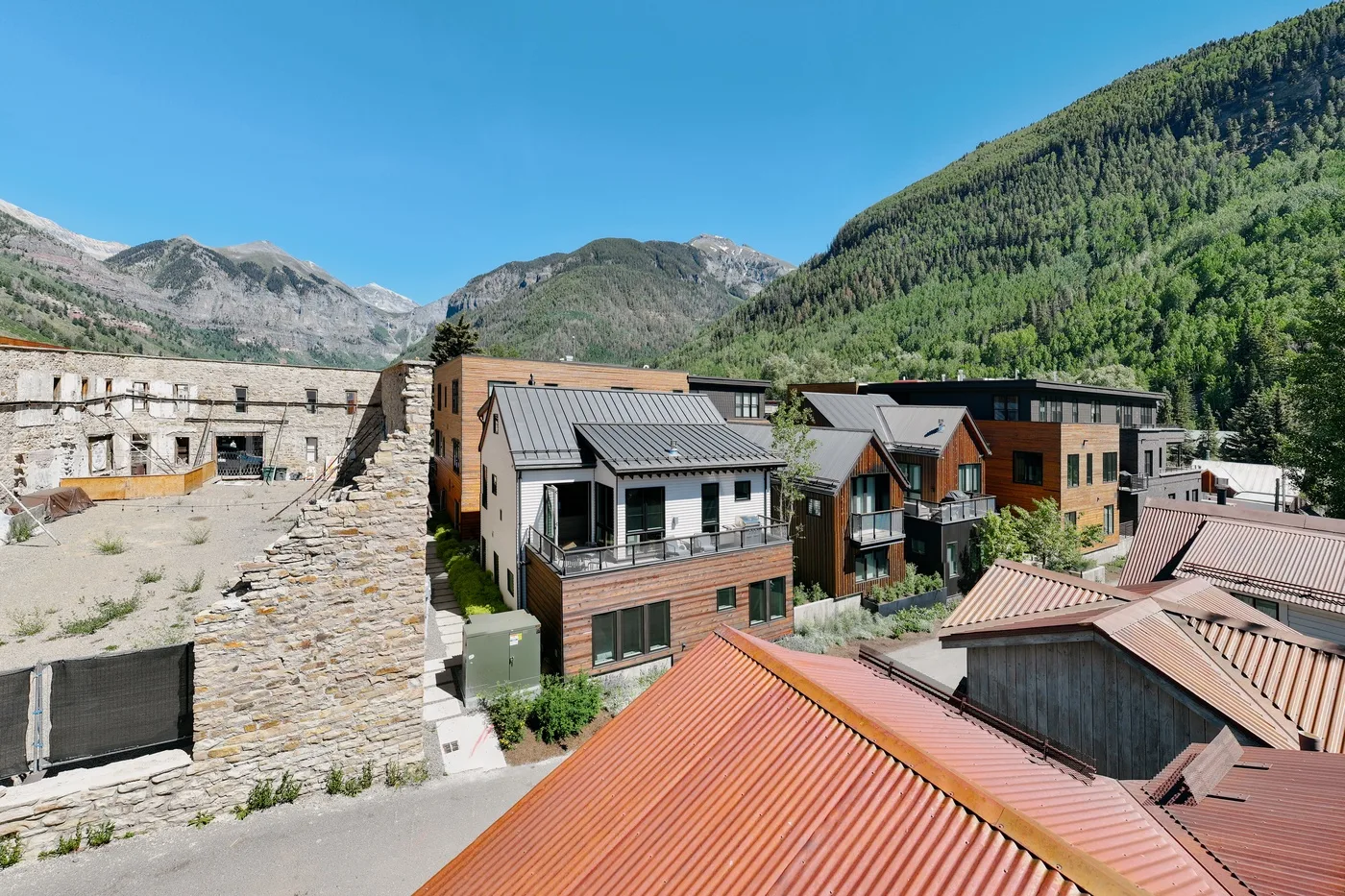 Un pueblo de montaña con edificios modernos se encuentra entre laderas verdes.