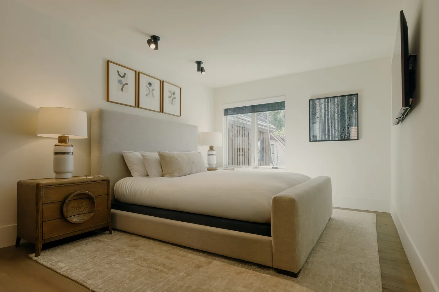 Un dormitorio con una cama grande, mesitas de noche y una ventana.