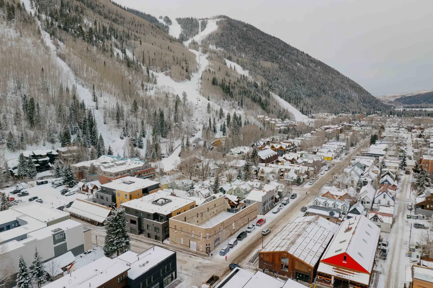Un pueblo cubierto de nieve se encuentra bajo laderas boscosas de esquí.