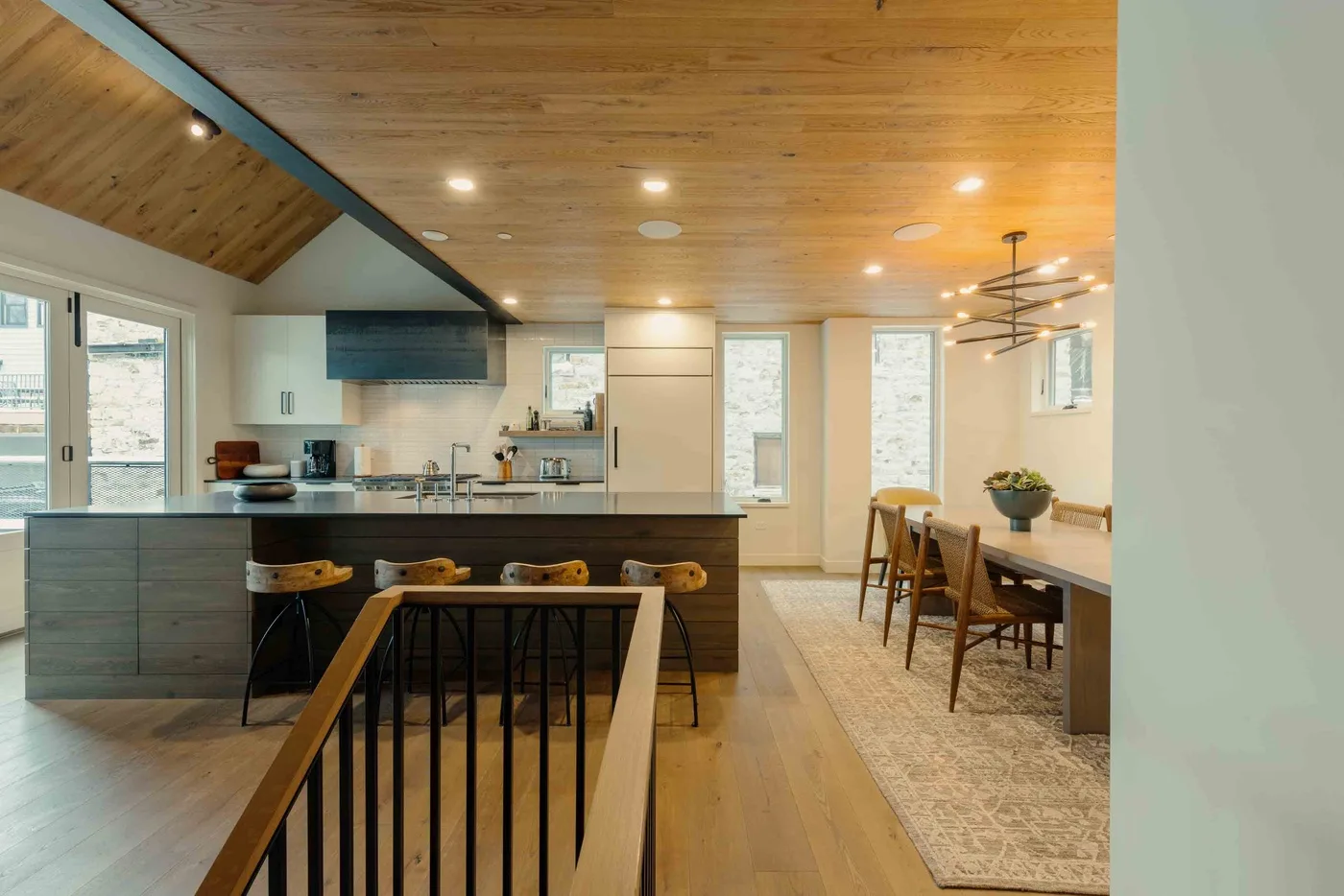 Una cocina y comedor abiertos con techo de madera e isla central.