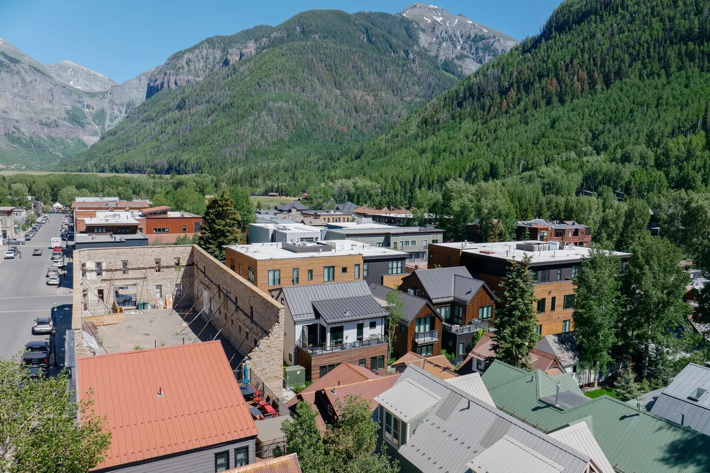 Un pueblo de montaña con edificios agrupados al pie de una cordillera boscosa.