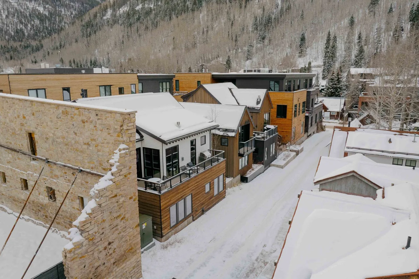 Edificios cubiertos de nieve se encuentran bajo una ladera boscosa.
