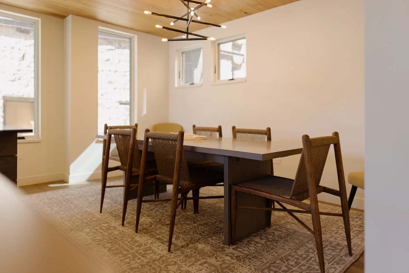 Un comedor con una gran mesa de madera y sillas bajo una lámpara de techo.