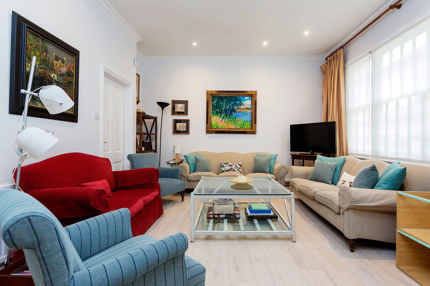 Una sala luminosa con asientos coloridos, una mesa de centro de vidrio y grandes ventanas.
