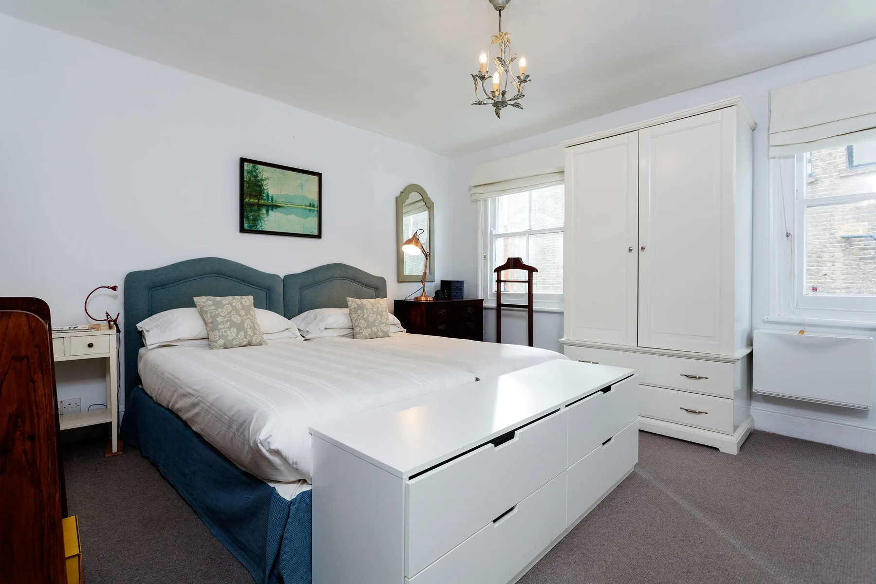 Dormitorio con una cama, armarios blancos y ventanas grandes.