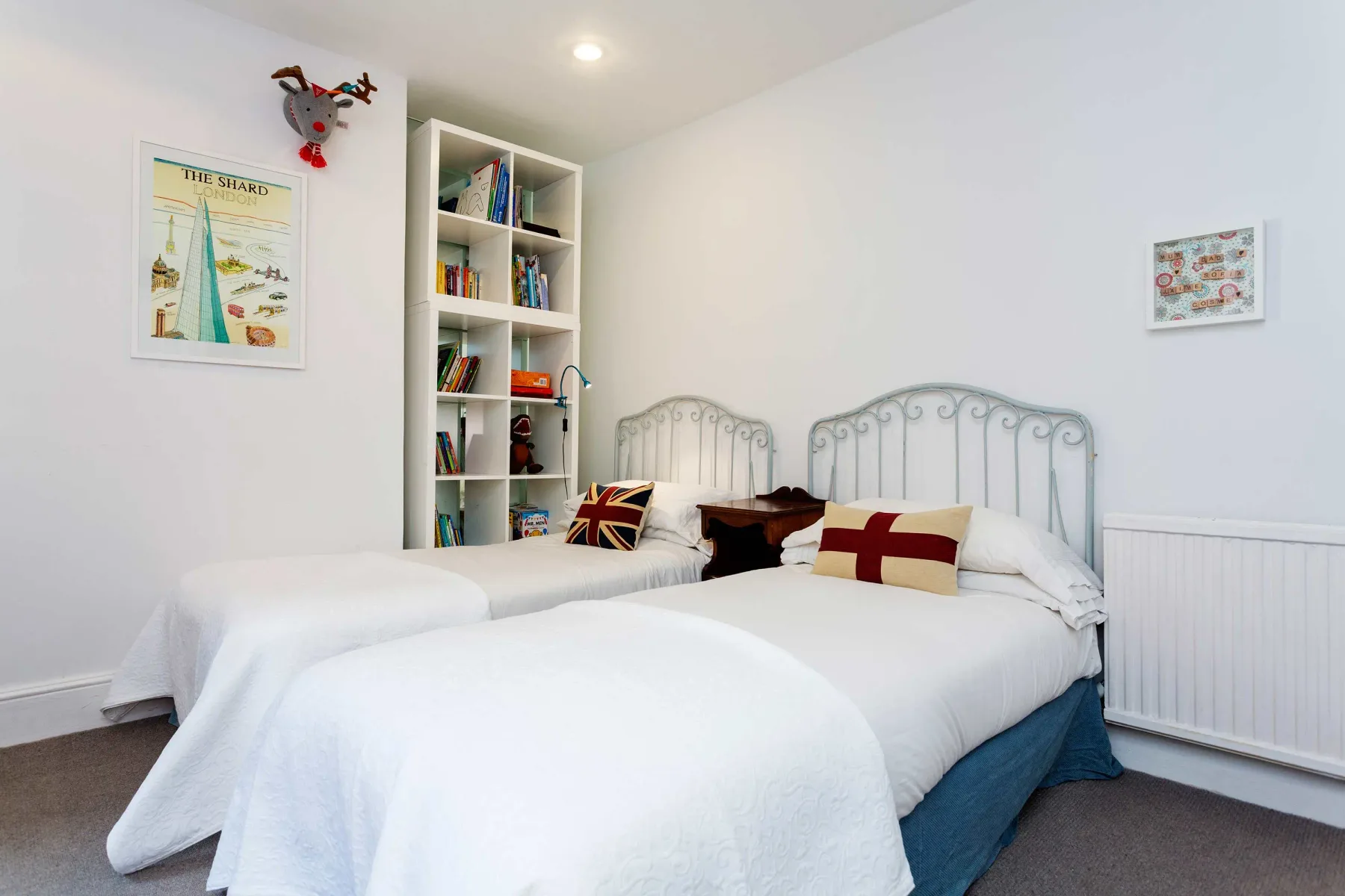 Un dormitorio luminoso con dos camas y una estantería.