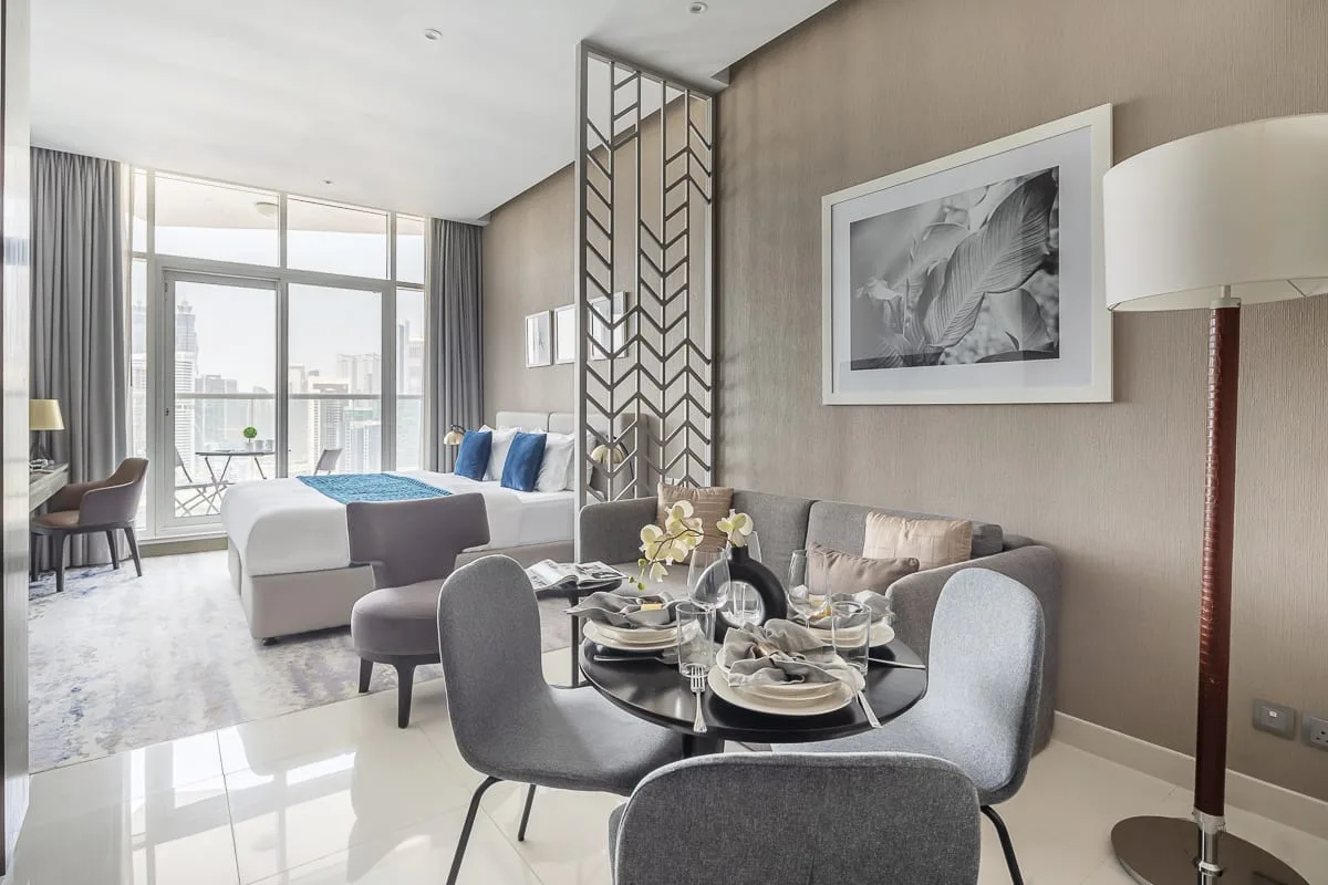 Una sala de estar y comedor moderna, con grandes ventanales y una mesa puesta.