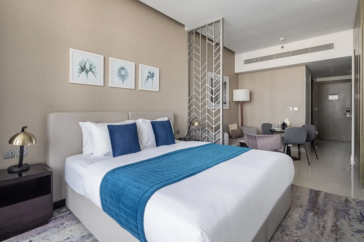 Un dormitorio moderno con una cama bien tendida y ropa de cama azul.