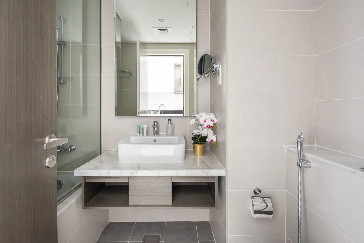 Un baño con azulejos, lavabo, espejo y ducha de vidrio.