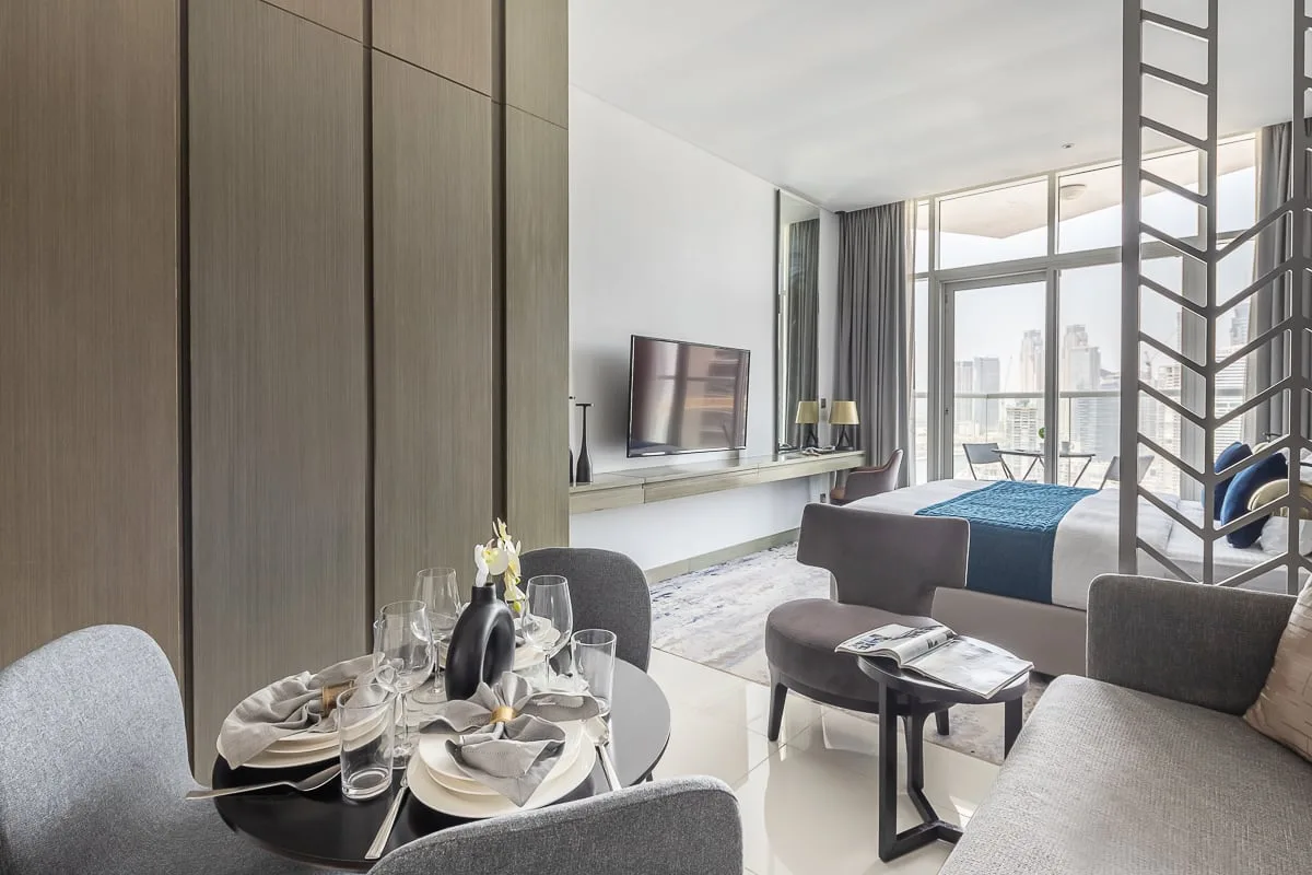 Una moderna zona de estar y comedor se abre a un dormitorio junto a ventanales.