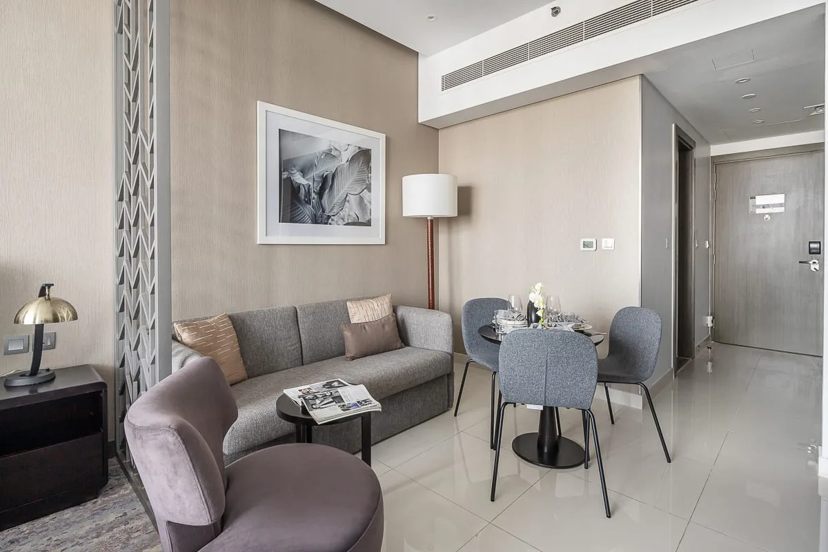 Una sala moderna con asientos alrededor de una mesa pequeña y una mesa de comedor cerca.
