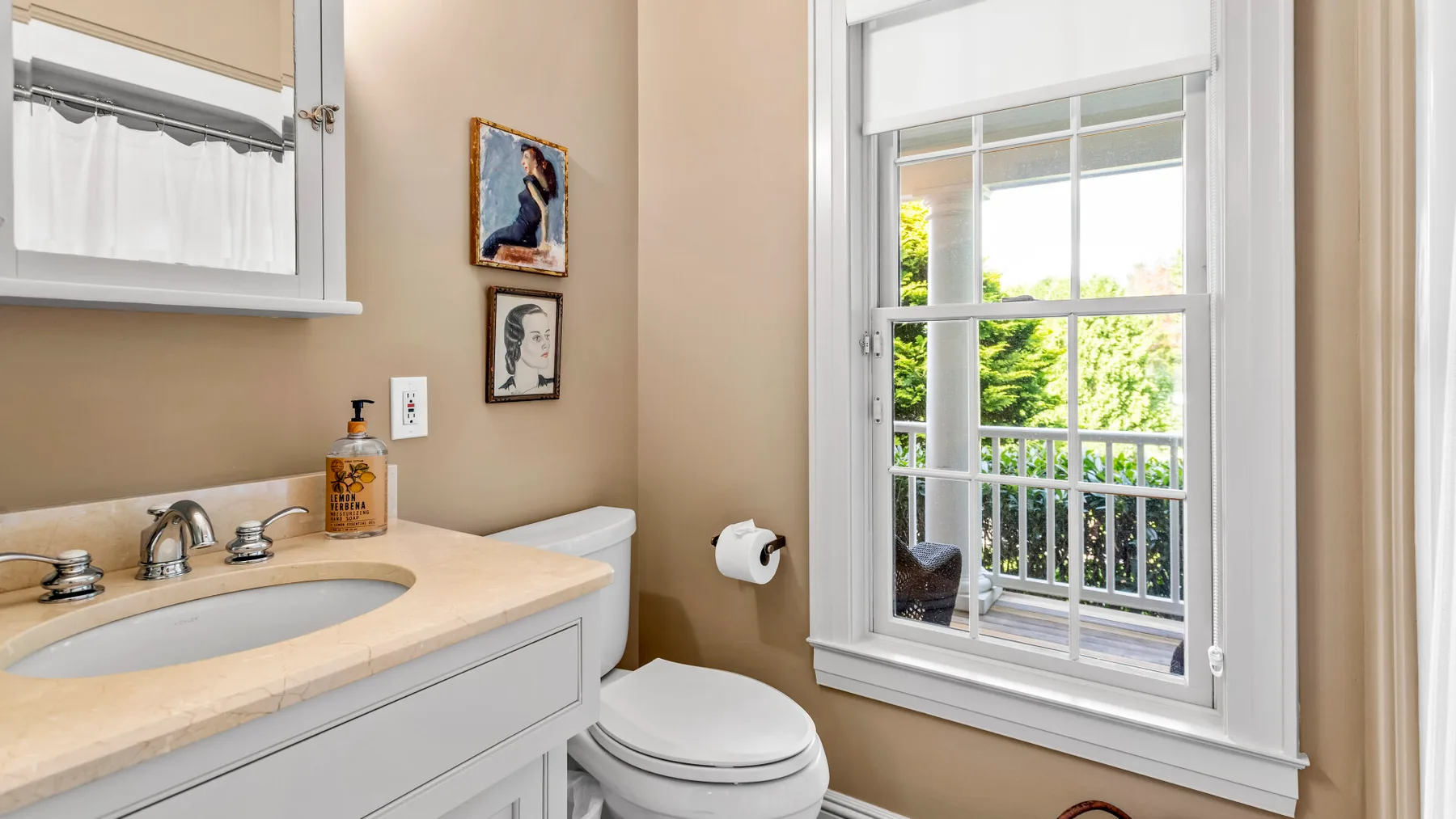 Un baño con lavabo, inodoro y una ventana grande con vista a la vegetación.