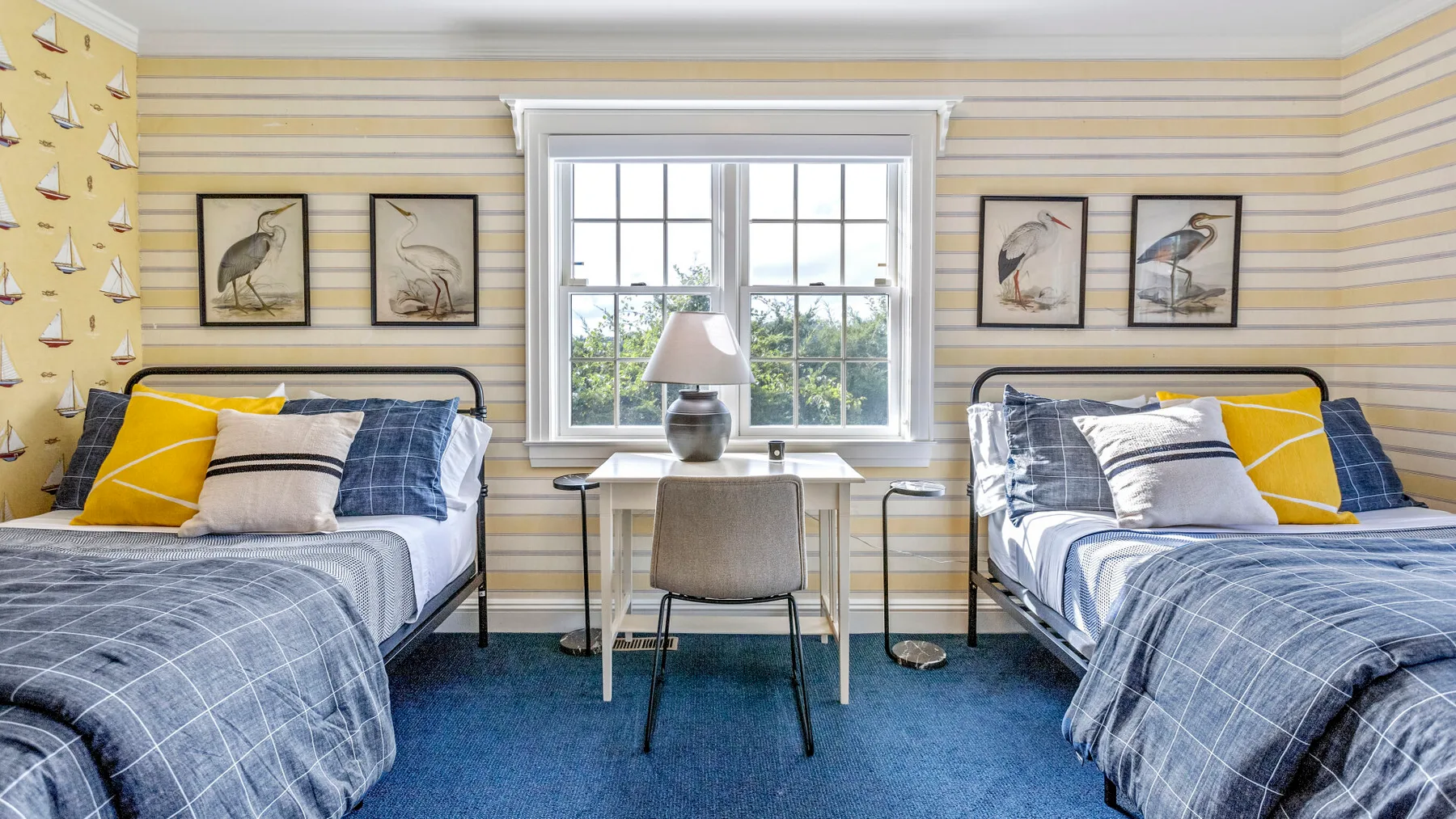 Un dormitorio con dos camas y un escritorio junto a la ventana.