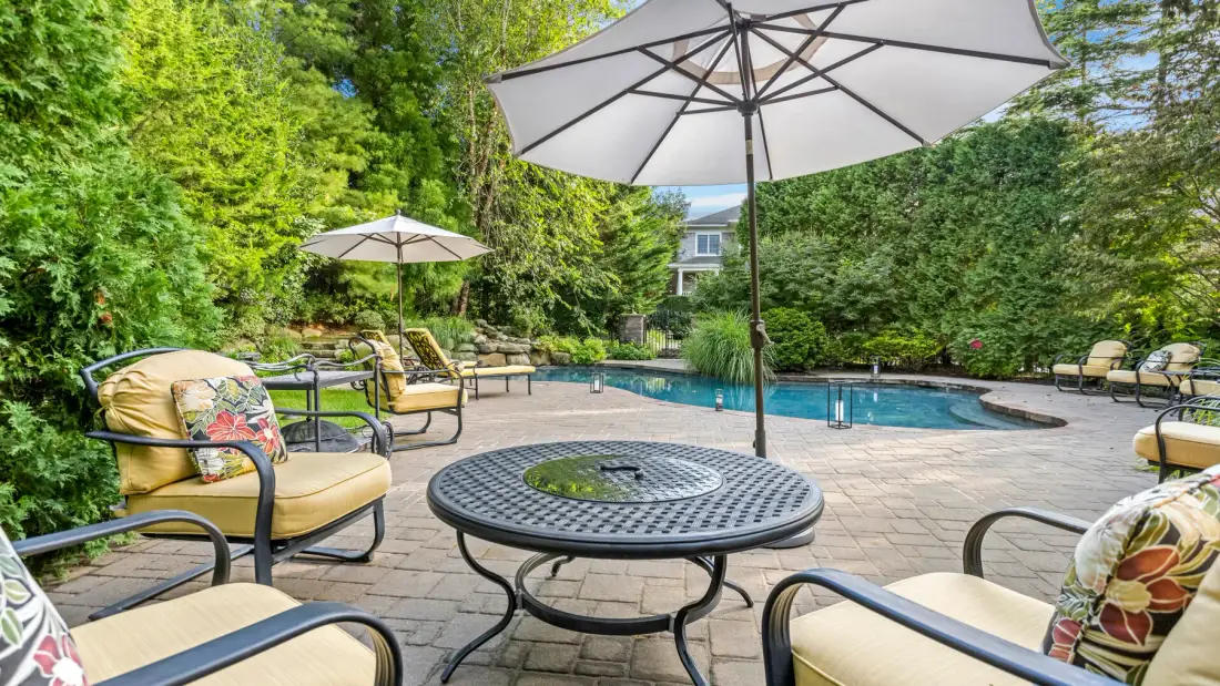 Un patio al aire libre con piscina, asientos y sombrillas grandes.